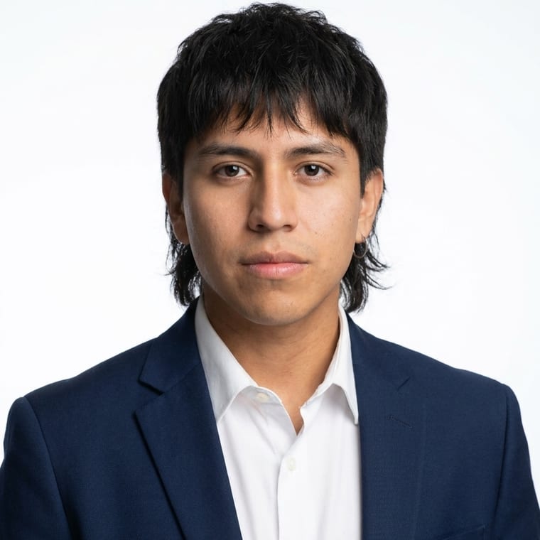 Young person in navy blazer and white shirt against plain background