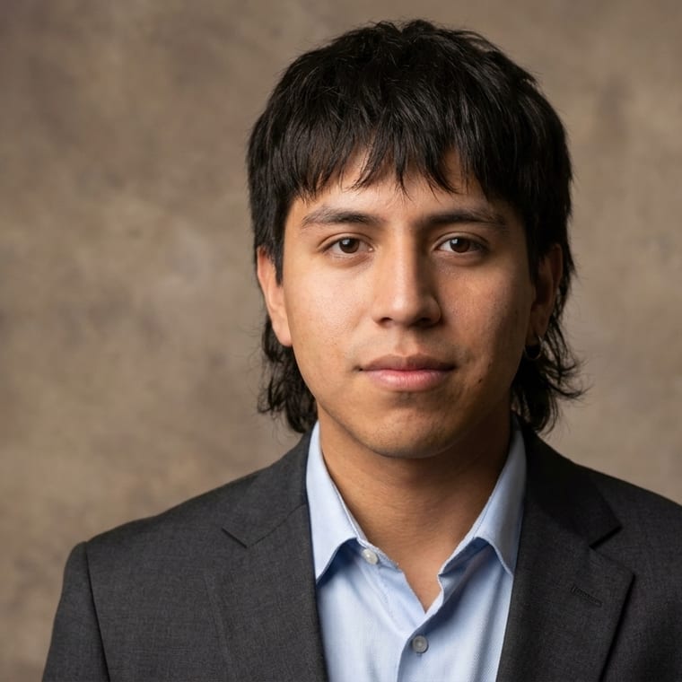 Young man in charcoal blazer against a mottled beige studio backdrop