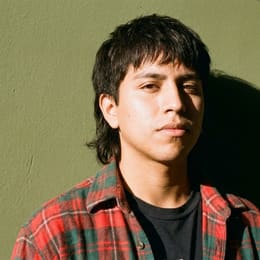 A person in their early twenties in a plain tee, lit with hard side sunlight.